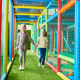 Two young girls walking hand-in-hand through a soft-play maze at Little Explorers Adventure Park, highlighting special events and group activities