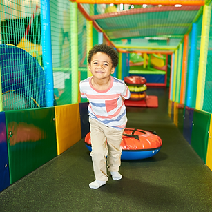 Young boy exploring a colorful indoor play structure, promoting membership benefits at Little Explorers Adventure Park
